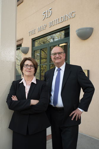 Attorneys Bruce Levitt and Shelley Slafkes stand in front of a beige building with the words "515 The Map Building" above their heads.